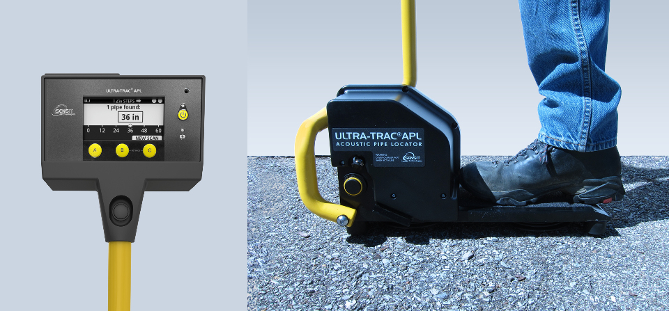 Acoustic pipe locator, top-down view. Round, bright yellow metal tubing extends from a small rectangular analog screen accompanied by round yellow buttons.