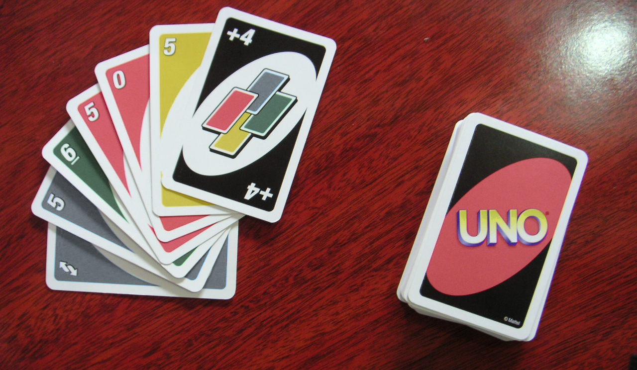 An Uno hand and deck are shown in which the colors are faded, particularly the green and blue colors, making them harder to differentiate.